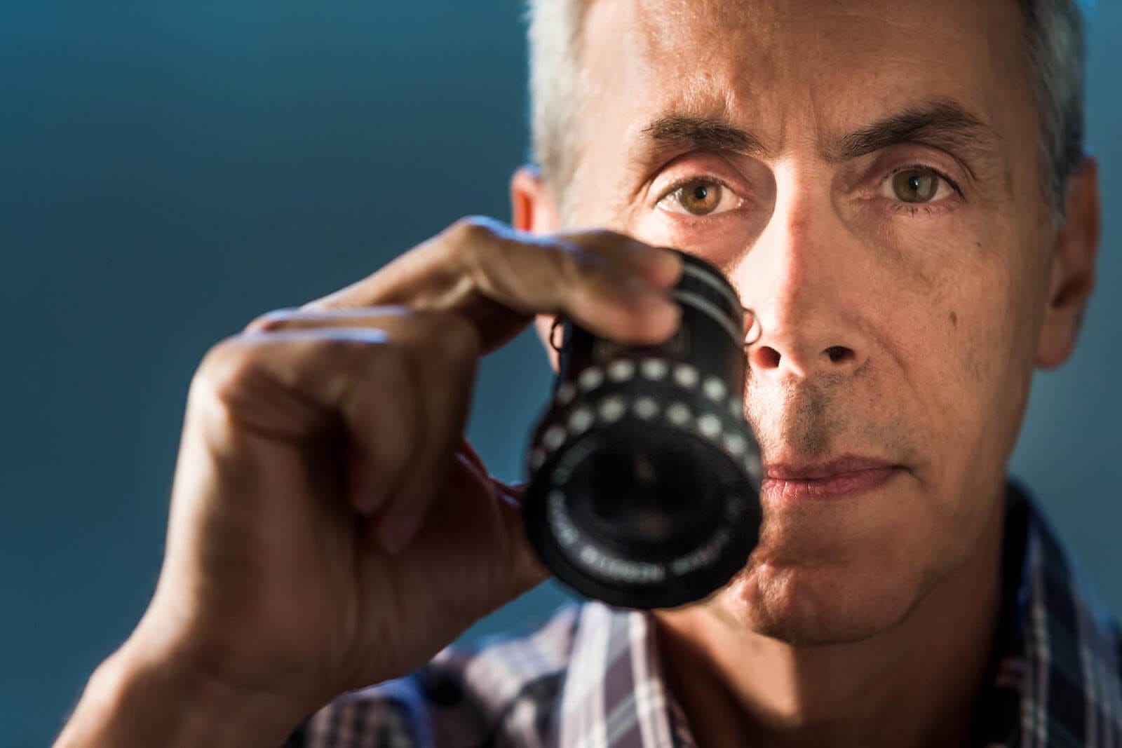 A portrait of filmmaker Aaron Weisblatt looking through a viewfinder