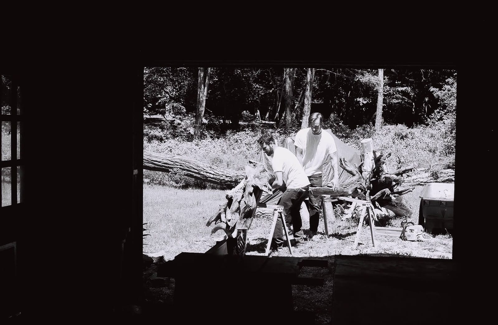 A black-and-white photo of Hudson Valley artist Brad Teasdale hauling driftwood into his studio