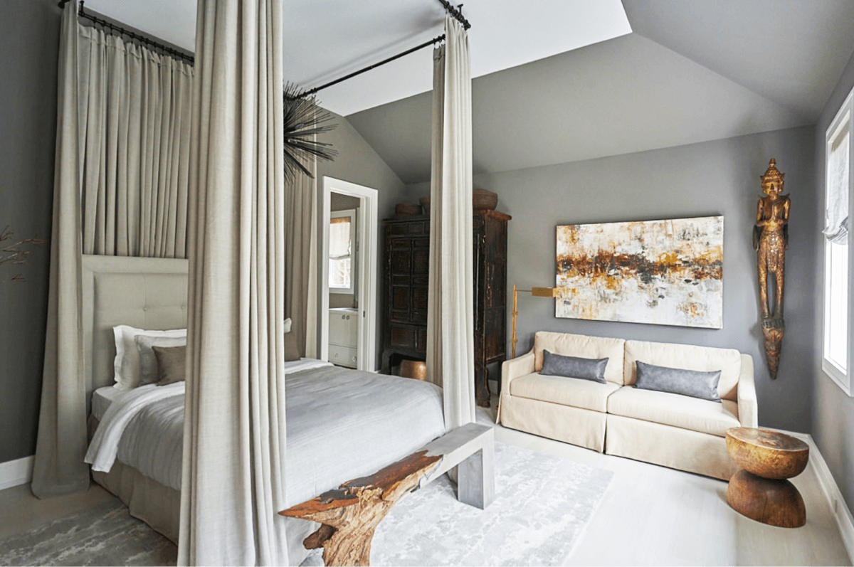 A Brad Teasdale-made mermaid bench at the foot of a bed in a chic bedroom