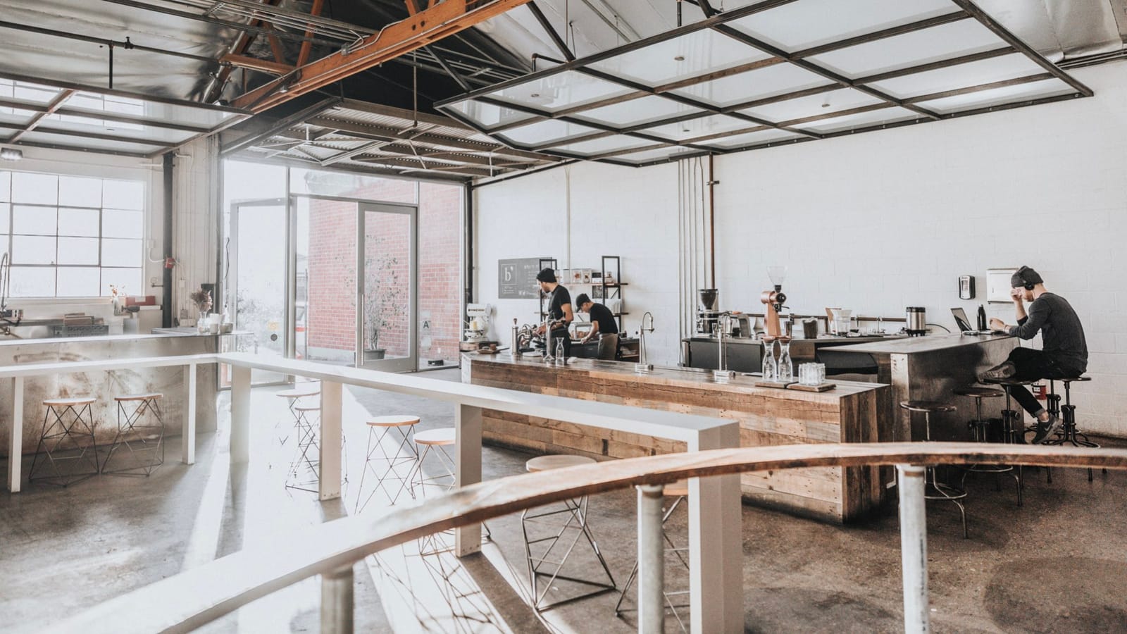 A typical hipster coffee shop with white walls, concrete floors, and wooden counter