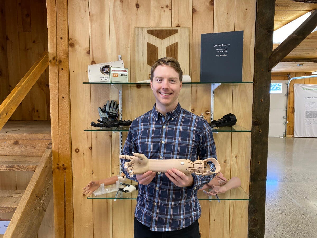 Easton LaChappelle standing in the Unlimited Tomorrow offices holding one of his robotic creations