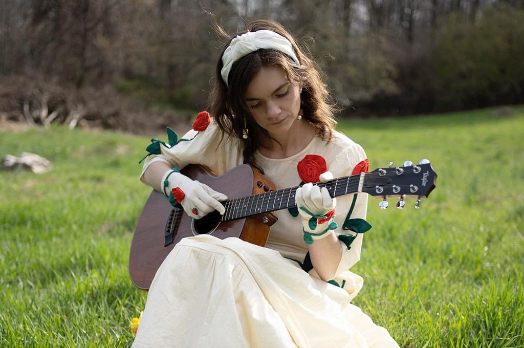 Musician Ginger Winn playing an acoustic guitar outdoors in the Hudson Valley