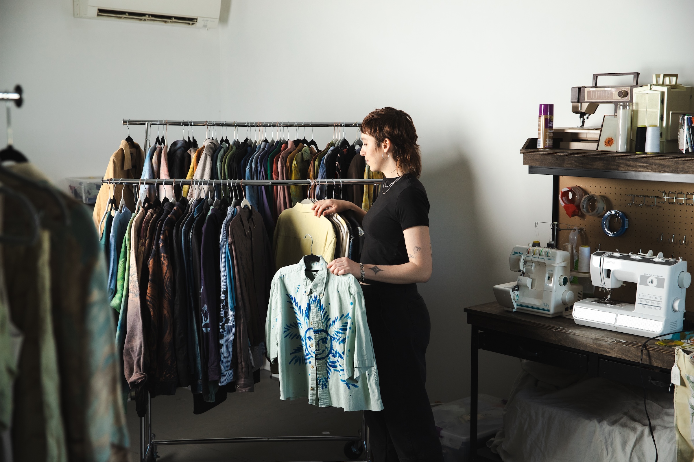 Sustainable fashion designer Moth Snow with racks of clothes and sewing machines