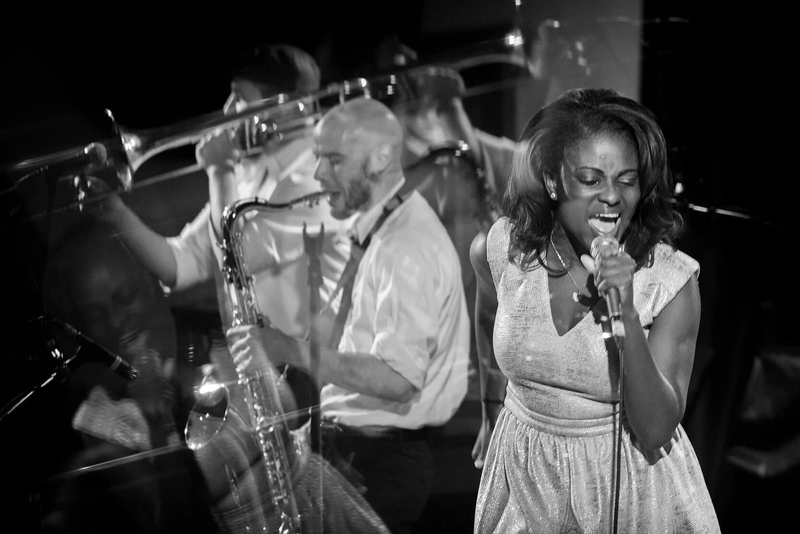 A black-and-white photo of NeeNee Rushie and The Big Takeover performing