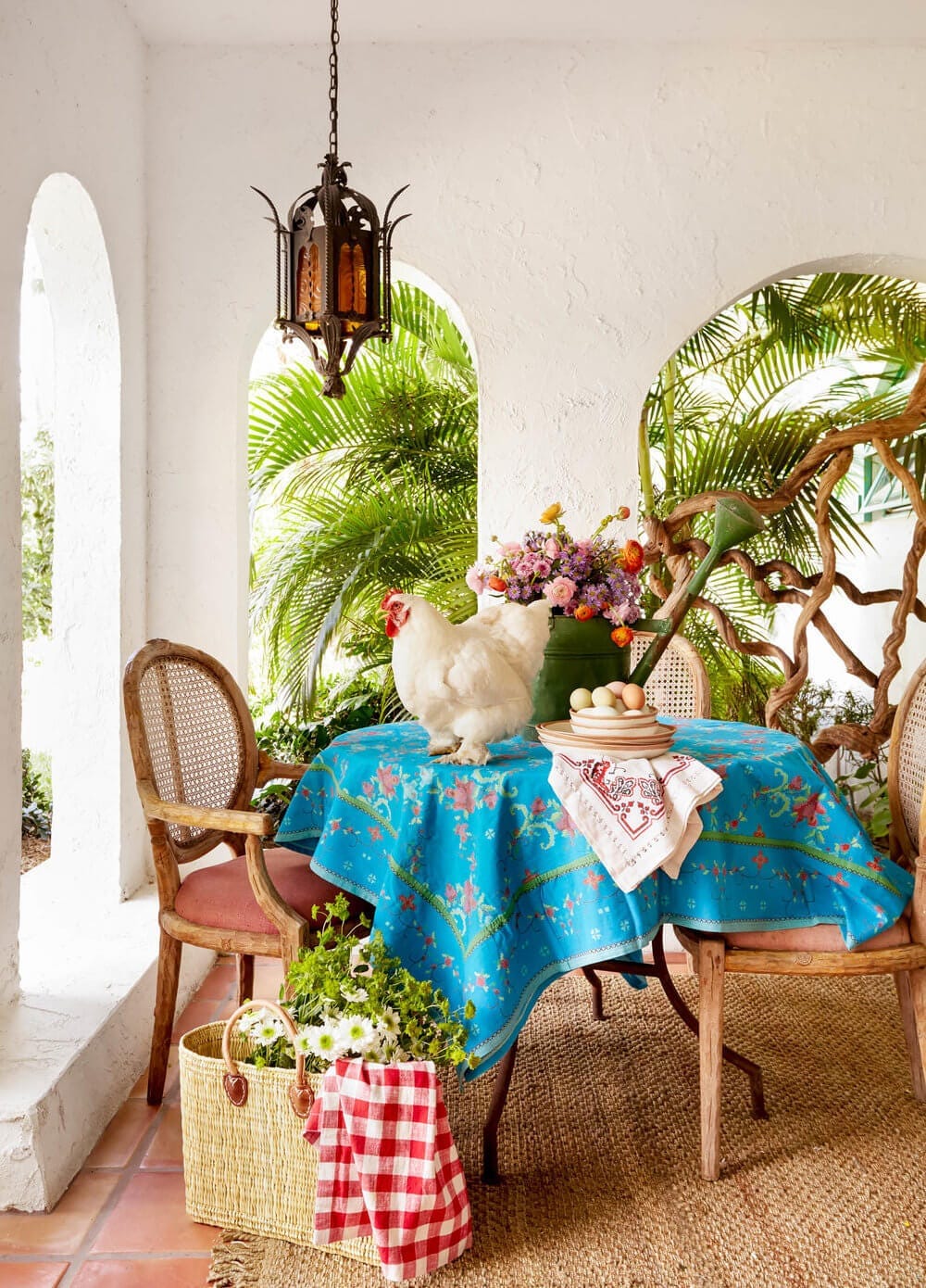 A tropical outdoor dining area with a rooster, photographed by Hudson Valley-based photographer Rikki Snyder